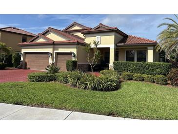 Charming home featuring a well-manicured lawn, complemented by lush landscaping and a tile roof at 4622 Grand Lakeside Dr, Palm Harbor, FL 34684