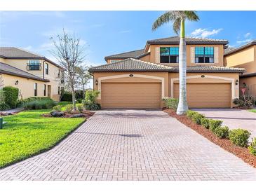 Well-maintained townhome showcasing a brick driveway, tropical landscaping, and a two-car garage at 6618 Grand Estuary Trl # 101, Bradenton, FL 34212