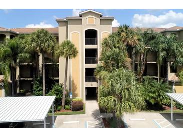 Condominium building with well-maintained grounds, palm trees, covered parking and secure entry at 7705 Grand Estuary Trl # 206, Bradenton, FL 34212