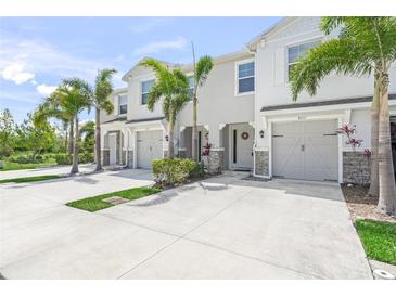 Charming townhomes with well-manicured lawns, decorative stone, and palm trees create a welcoming curb appeal at 8711 Palmer Park Cir, Sarasota, FL 34238