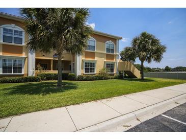Inviting multi-story condo boasts well-manicured lawn, mature palm trees, and neutral exterior paint at 3015 Chianti Ct # 104, Sarasota, FL 34237