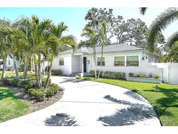 Charming single-story home with a circular driveway, lush landscaping and mature palm trees at 322 35Th Ne Ave, St Petersburg, FL 33704