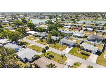 This aerial view shows a neighborhood with single-Gathering homes and a serene lake at 440 Redwood Rd, Venice, FL 34293