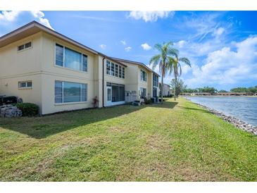 Exterior view of the condo with a lake and lush green lawn with palm trees in the background at 4454 Narraganset Trl # 94A, Sarasota, FL 34233