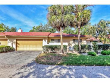 Inviting home featuring a red tile roof, two-car garage, and mature landscaping with palm trees at 6414 Sun Eagle Ln, Bradenton, FL 34210
