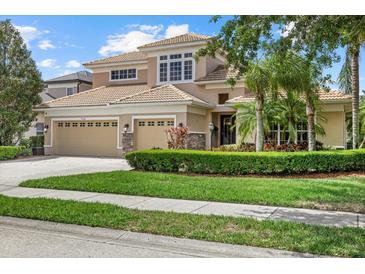 Stunning two-story home featuring a three-car garage, well-manicured lawn, and beautiful tropical landscaping at 6532 Coopers Hawk Ct, Lakewood Ranch, FL 34202