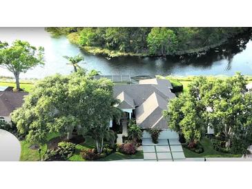 Beautiful aerial view of a single Gathering home on the water with lush landscaping and a screened in pool at 8687 Woodbriar Dr, Sarasota, FL 34238