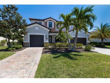 Beautiful two-story home boasts a well-manicured lawn, paver driveway, a two-car garage and lush tropical landscaping at 13409 Ramblewood Trl, Bradenton, FL 34211