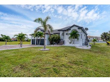 A beautiful two-story house with a well-manicured lawn and lush tropical landscaping at 24017 Peppercorn Rd, Punta Gorda, FL 33955