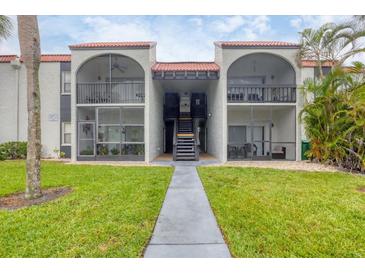 Condo building with stucco exterior, red tile roof, and open balconies overlooking a green lawn at 3251 Beneva Rd # 104, Sarasota, FL 34232