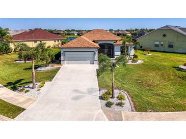 Charming single-story home with a well-manicured lawn, palm trees, and a two-car garage at 12830 24Th Street E Cir, Parrish, FL 34219