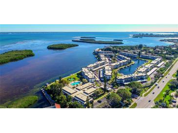 Stunning aerial view of waterfront condos with pool, boat docks, and lush landscaping, offering serene coastal living at 4350 Chatham Dr # E-105, Longboat Key, FL 34228