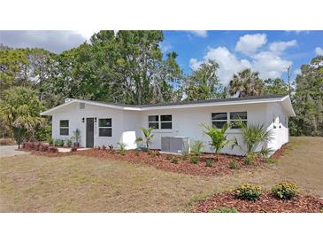 Charming single-story white home featuring a well-maintained lawn with mulch and updated landscaping at 4823 Linwood St, Sarasota, FL 34232