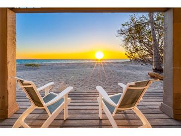 Stunning sunset view from beachside home with two chairs on the porch overlooking the ocean at 8592 Hidden Lagoon Rd, Sarasota, FL 34242