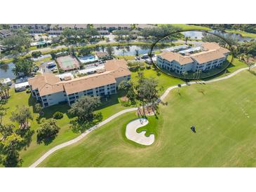 Scenic aerial view of property featuring well-maintained landscaping, golf course, pond, and tennis court at 9630 Club South Cir # 6209, Sarasota, FL 34238