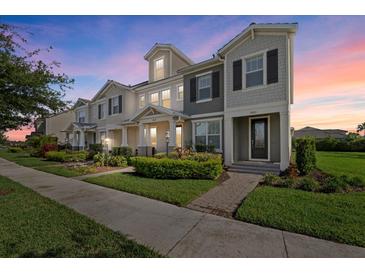 Beautiful townhome showcasing manicured landscaping and a charming, symmetrical facade at dusk at 12029 Cranston Way, Lakewood Ranch, FL 34211