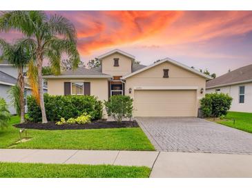 Charming single-Gathering home featuring a well-manicured lawn, lush landscaping, and a brick-paved driveway at 12592 Ryegrass Loop, Parrish, FL 34219