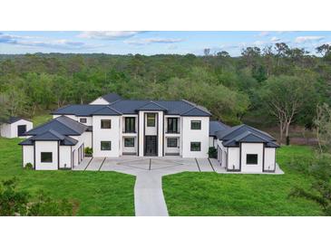 Stunning modern home with a black metal roof, white exterior, and lush green lawn at 20307 74Th E Ave, Bradenton, FL 34202