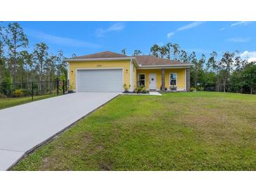 Charming yellow single-story home with a well-maintained lawn and a long driveway leading to an attached two-car garage at 27207 Treadmill Dr, Punta Gorda, FL 33955