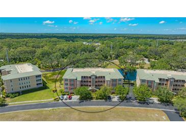 Aerial view of charming condo buildings with manicured lawns and lush trees near a tranquil pond in a desirable community at 5242 Manorwood Dr Dr # 3A, Sarasota, FL 34235