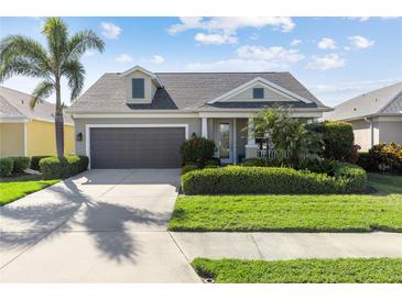 Charming single-story home featuring a well-manicured lawn, a two-car garage, and mature palm trees at 6936 White Willow Ct, Sarasota, FL 34243