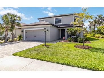 Charming two-story home with a well-manicured lawn, gray exterior, and a two-car garage at 9061 Luna Ln, Sarasota, FL 34241
