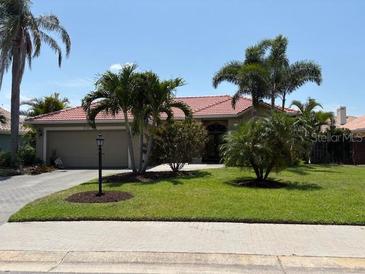 Well-maintained single-story home featuring a red tile roof, lush landscaping, and a spacious two-car garage at 3724 71St E Ter, Sarasota, FL 34243