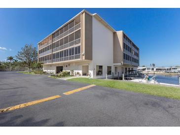 Low angle view of a waterfront condo with parking, green space, and boat dock on a sunny day at 1714 69Th W Ave # C402, Bradenton, FL 34207