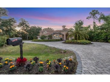 Elegant Mediterranean-style home featuring a circular driveway and lush landscaping at 3905 Trentwood Pl, Sarasota, FL 34243