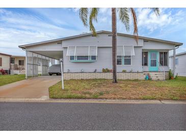 Charming single-story home featuring a covered carport, turquoise door, and tropical landscaping at 4312 14Th E St, Ellenton, FL 34222