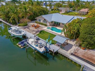 Aerial view showcasing a home with a private pool, boat dock, and waterfront access, ideal for boating enthusiasts at 519 74Th St, Holmes Beach, FL 34217