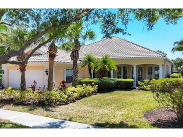 Charming single-story home with tile roof, lush landscaping and mature palm trees in the front yard at 5881 Girona Pl, Sarasota, FL 34238