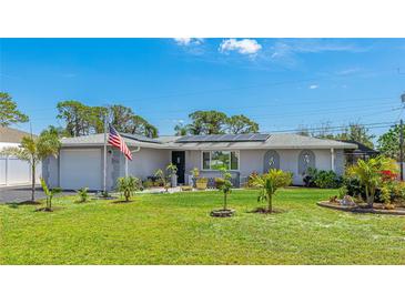 Charming single-story home featuring a well-manicured lawn, mature trees, and solar panels on the roof at 959 Cumberland Rd, Venice, FL 34293