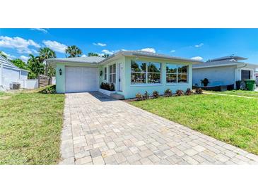 Inviting single-story home featuring a well-manicured lawn, paver driveway, and a charming light green exterior at 148 N Blvd Of The Presidents, Sarasota, FL 34236