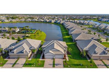 Aerial view of new homes in a community surrounding a scenic lake and community pool at 17827 Cherished Loop, Lakewood Ranch, FL 34211