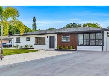 Charming single-story home with a well-manicured lawn and a modern white and wood facade at 1921 Fern Ave, Sarasota, FL 34235