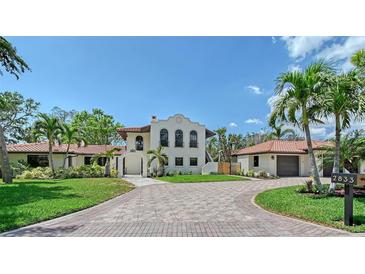 Stunning two-story home with a clay tile roof and circular driveway, surrounded by lush landscaping at 2833 Bay Shore Cir, Sarasota, FL 34234