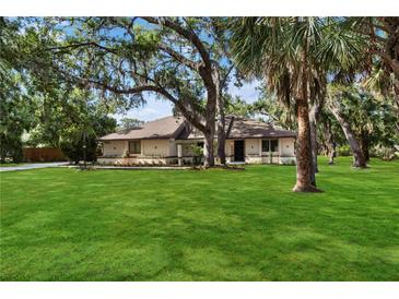 Charming home with a lush green lawn and mature trees offering ample shade at 4916 Hidden Oaks Trl, Sarasota, FL 34232