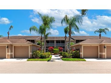 Exterior view of condo with a garage, mature landscaping, well-maintained complex under a partly cloudy blue sky at 5251 Mahogany Run Ave # 521, Sarasota, FL 34241