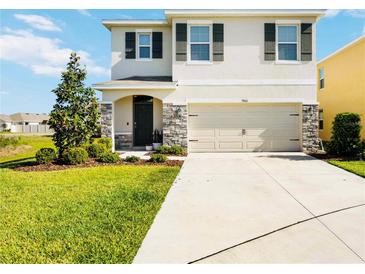 Charming two-story home with a two-car garage, stone accents, and a well-manicured lawn at 5800 Elegant Orchid Way, Sarasota, FL 34232