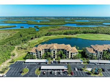 Beautiful aerial view of the community featuring a body of water, golf course, and covered parking at 7005 River Hammock Dr # 402, Bradenton, FL 34212