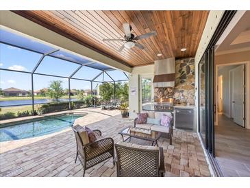 An amazing outdoor kitchen, pool and lounge are shown on the screened-in lanai at 7113 Whittlebury Trl, Bradenton, FL 34202