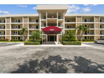Inviting condo exterior with palm trees and well-maintained landscaping, featuring a covered entrance and ample parking at 7461 W Country Club Dr N # 408, Sarasota, FL 34243