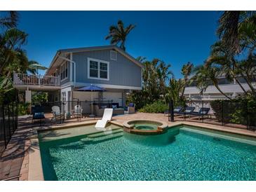 Gorgeous pool and patio with a hot tub, lounge chairs, and tropical ambiance at 750 Tarawitt Dr, Longboat Key, FL 34228