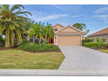 Charming single-story home with a well-manicured lawn, complemented by lush tropical landscaping and an attached two-car garage at 1363 New Forest Ln, Osprey, FL 34229