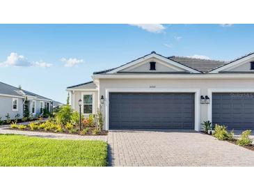 Beautiful home exterior with a two-car garage, brick paved driveway, and landscaped lawn at 16202 Isola Pl, Bradenton, FL 34211