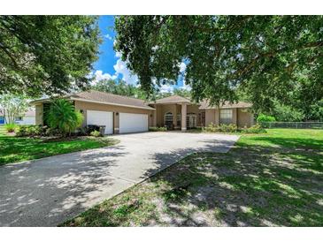 Spacious home exterior with a long driveway, mature trees, green grass, and a two-car garage at 2611 221St E St, Bradenton, FL 34211