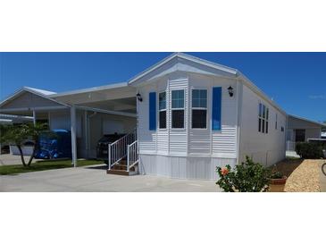 Bright exterior of a well-maintained mobile home with blue shutters, white siding, and a convenient carport at 3333 26Th E Ave # 1257, Bradenton, FL 34208