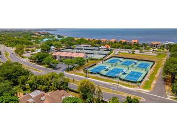 An aerial view showcasing multiple tennis courts next to the Gulf of Mexico and nearby condominiums at 4510 El Conquistador Pkwy # 105, Bradenton, FL 34210