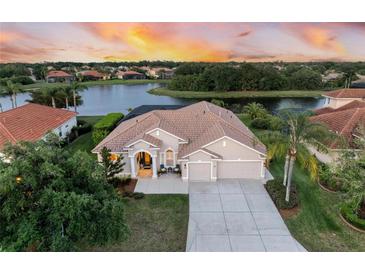Waterfront home with tile roof, screened lanai and mature landscaping at sunset at 251 Dove Trl, Bradenton, FL 34212